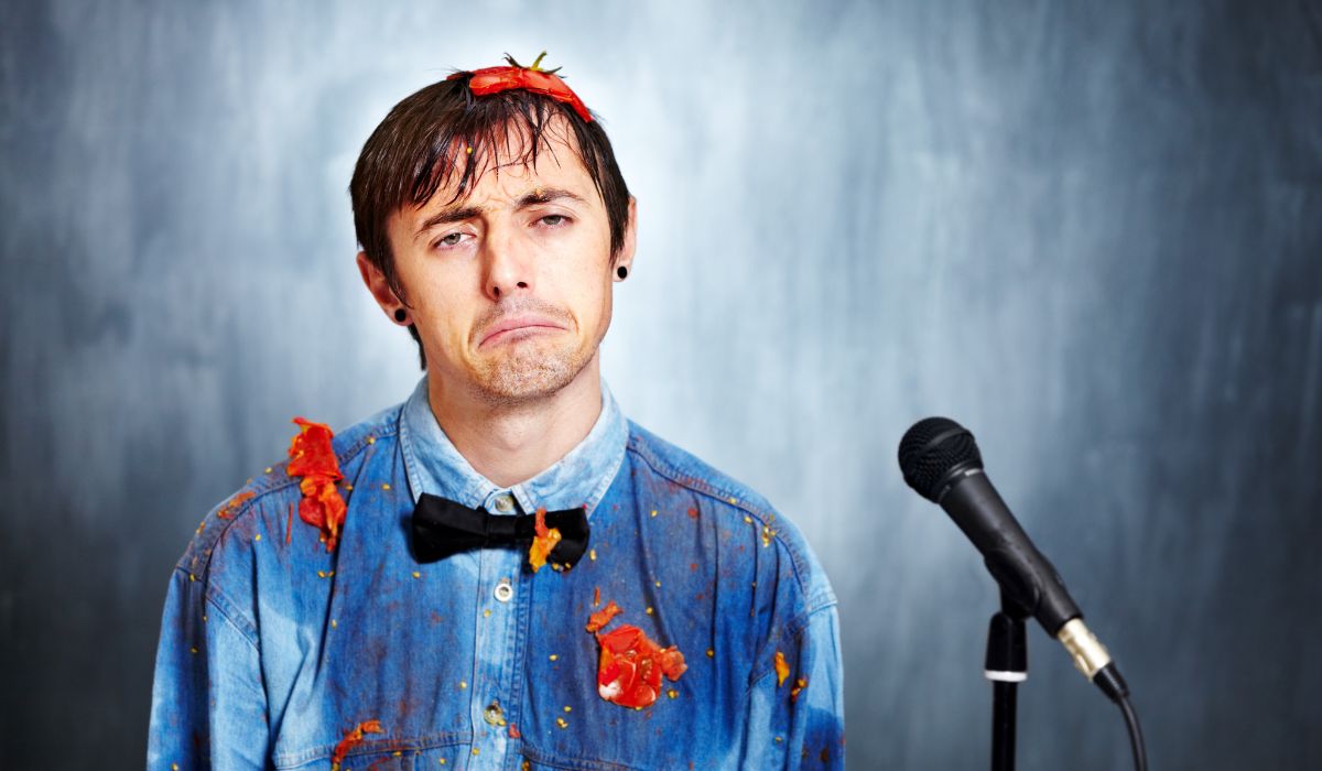 Man with smashed tomatoes on his shirt standing at microphone